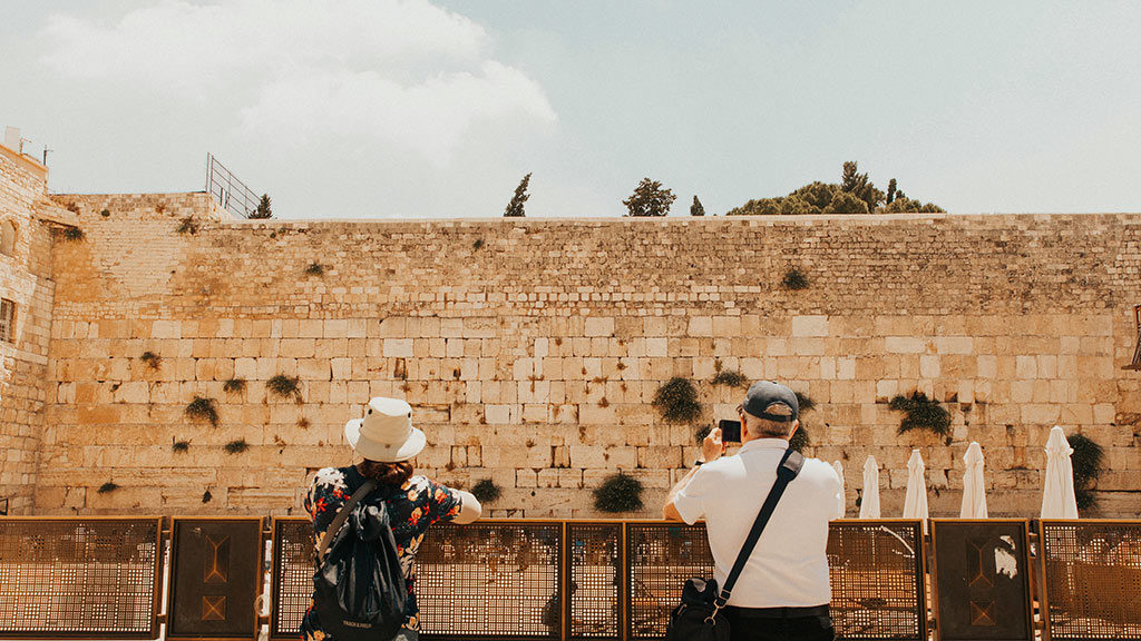 two people standing and looking at the western wall
