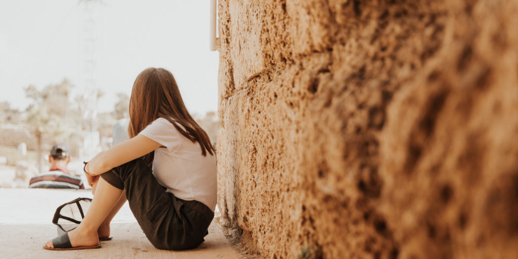girl sitting next to a wall