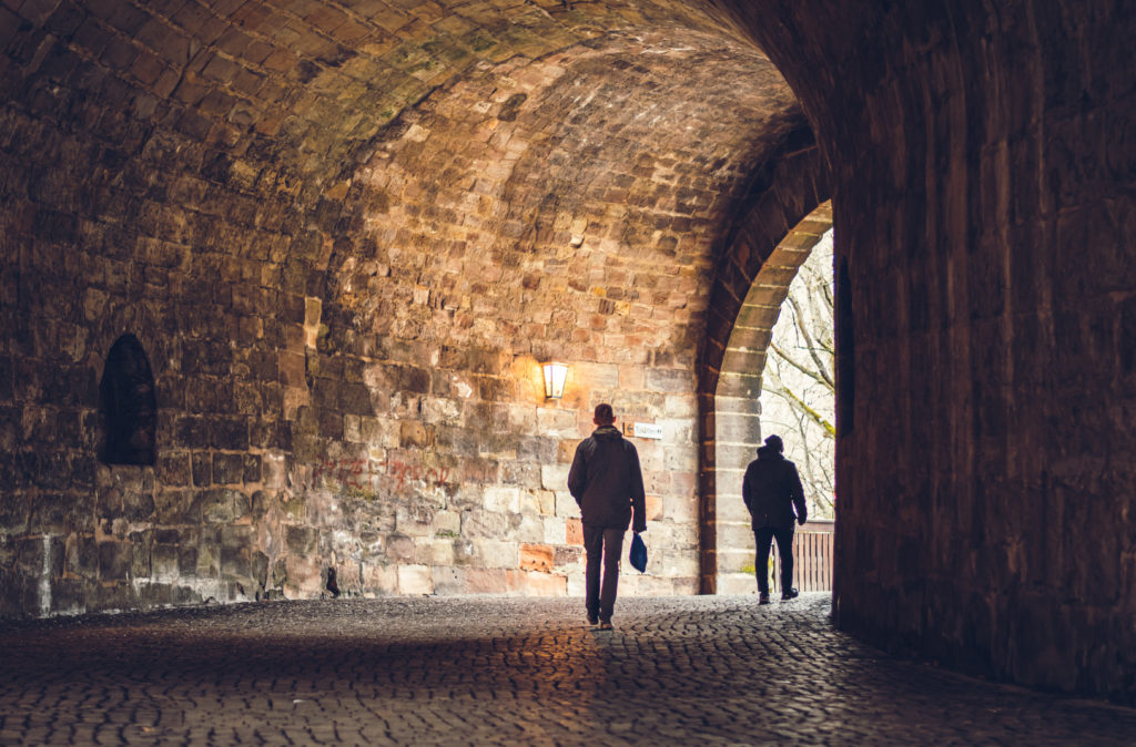 two men walking through a tunnel in the city