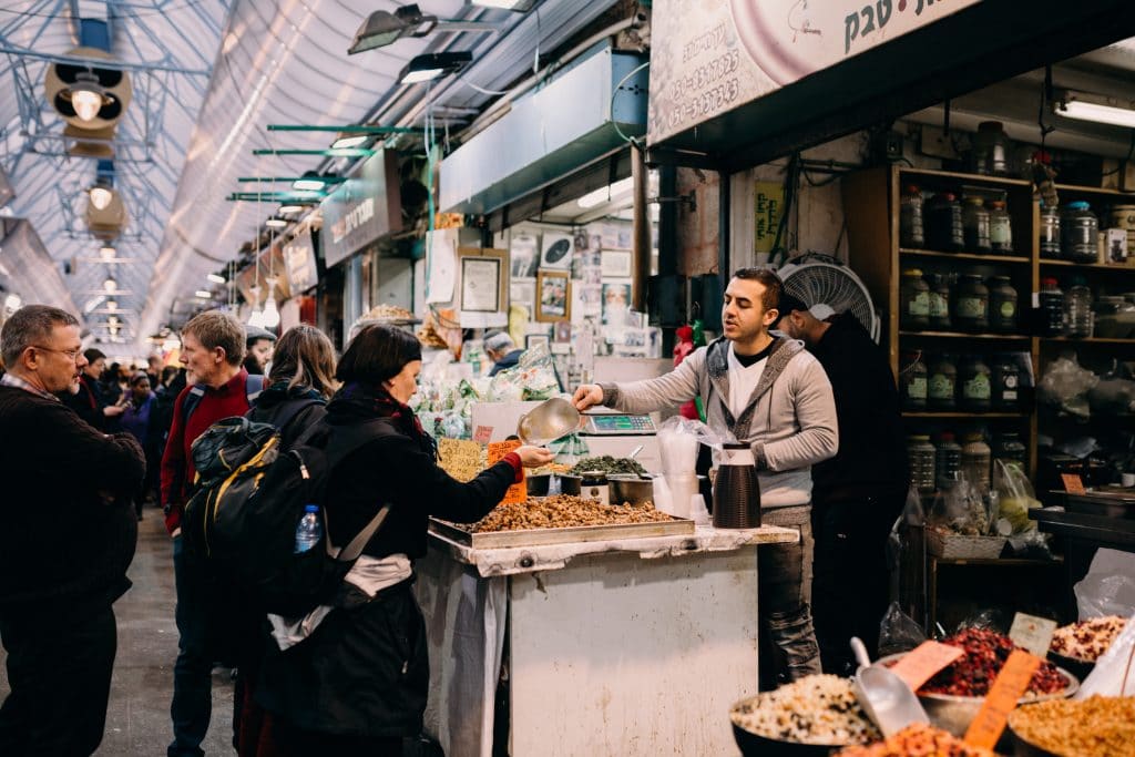 woman buying food is a stand at the shuk